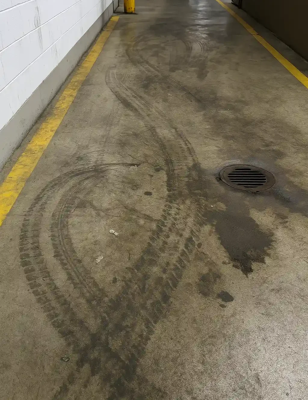 Industrieboden vor der Grundreinigung: Reifenabrieb und Ölspuren in einer Halle.